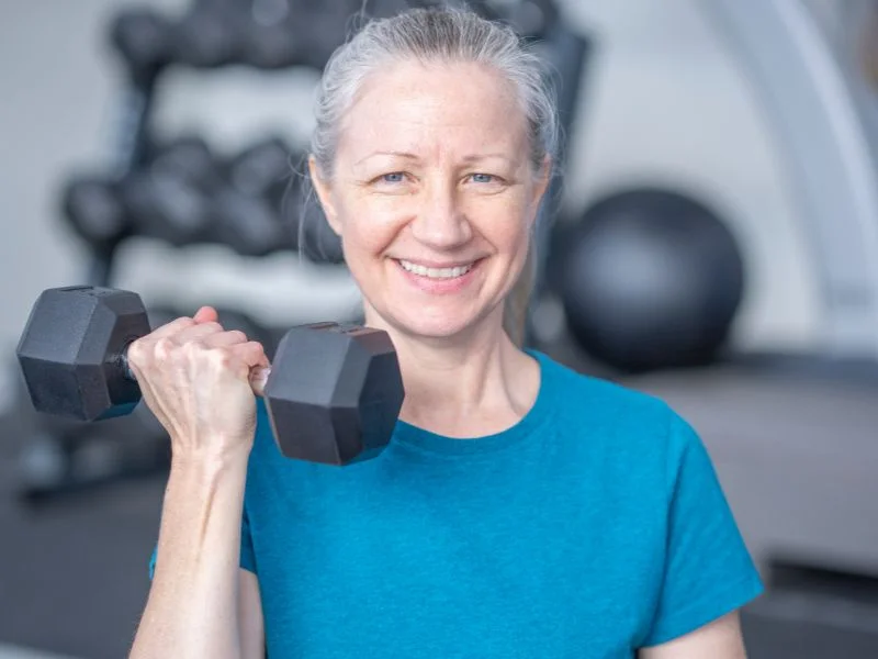 A person smiling and laughing while doing a strength training exercise