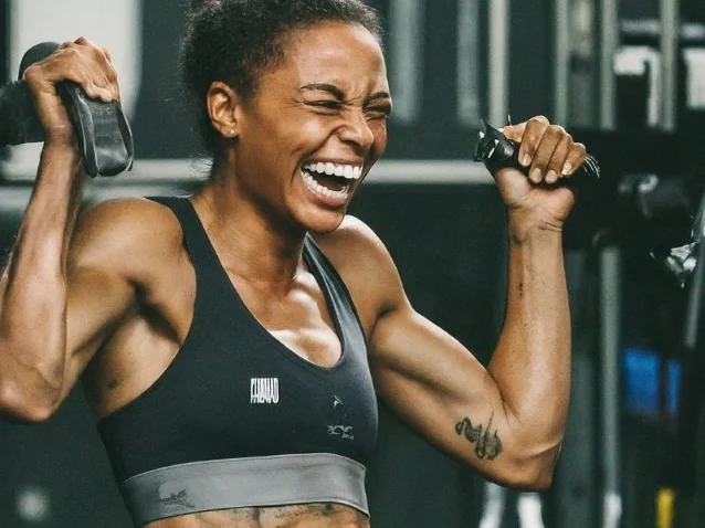 A person smiling and laughing while doing a strength training exercise