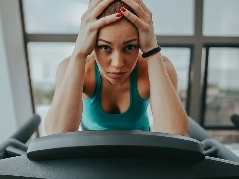Frustrated person on a treadmill, looking exhausted and unmotivated.