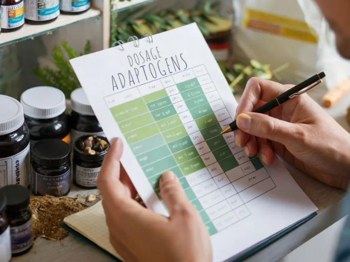 A close-up photograph of a person carefully examining a dosage chart for adaptogens