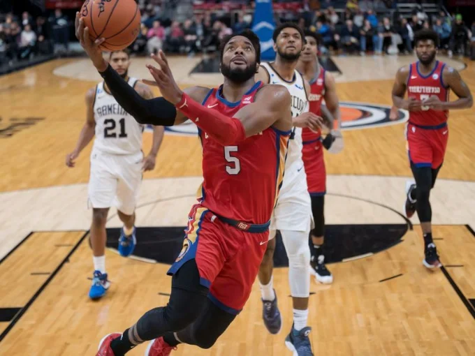 A basketball player in action on the court, wearing a red jersey with the number 5