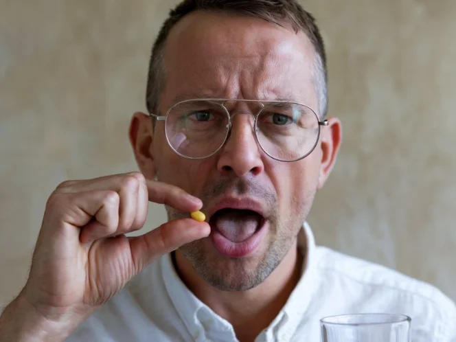 A medium shot image of a person taking a supplement