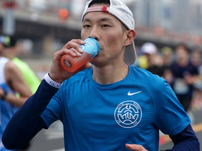 A photo of a marathon runner sipping a sports drink during a race