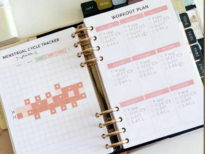 A photo of a planner open to a page with a menstrual cycle tracker and a workout plan