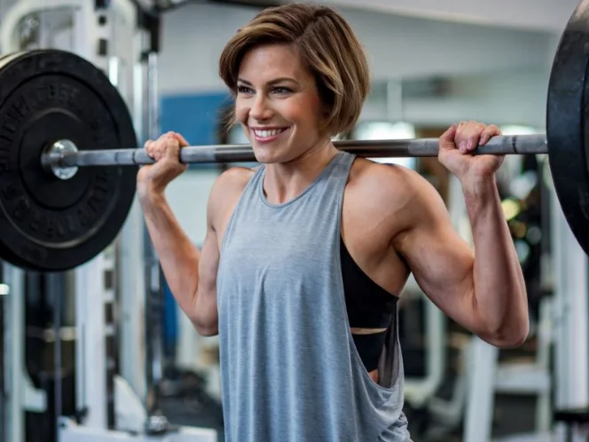 A photo of a woman with short brown hair wearing a gray tank top and black leggings