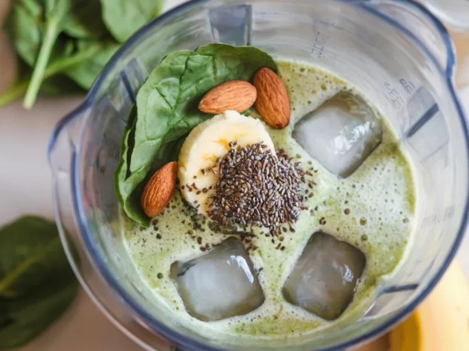 A photo of a workout recovery shake. There's a blender filled with a green shake