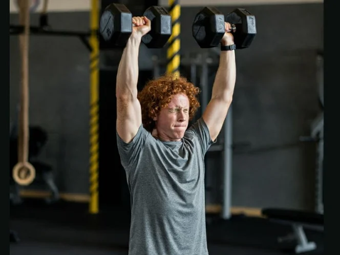 A person performing a standing dumbbell overhead press