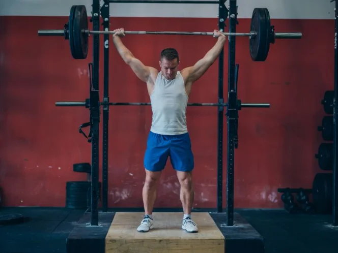 A person performing standing barbell calf raises