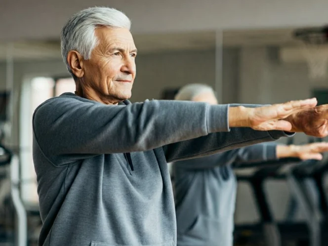 A senior performing gentle warm-up stretches, such as arm circles and leg swings