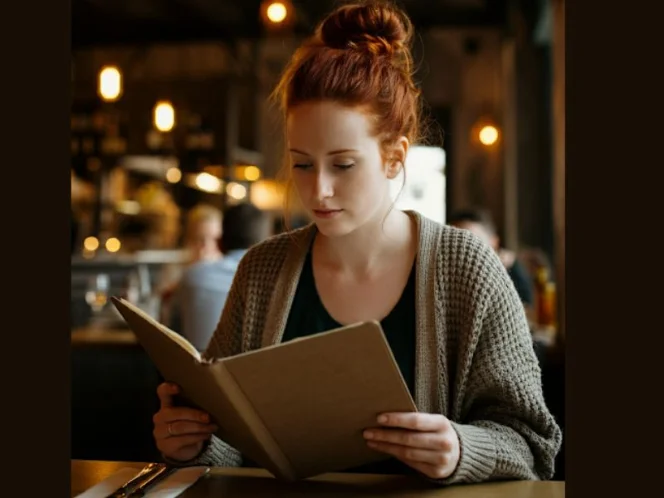 A person looking at a menu with a thoughtful expression, representing the potential challenges of navigating social situations and meal planning on a plant-based diet