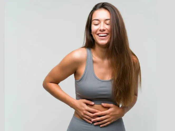 A person smiling and holding their stomach, showcasing a sense of well-being associated with a healthy gut